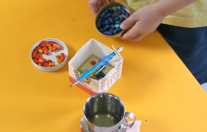 Adding crayon pieces to scented milk carton candles.