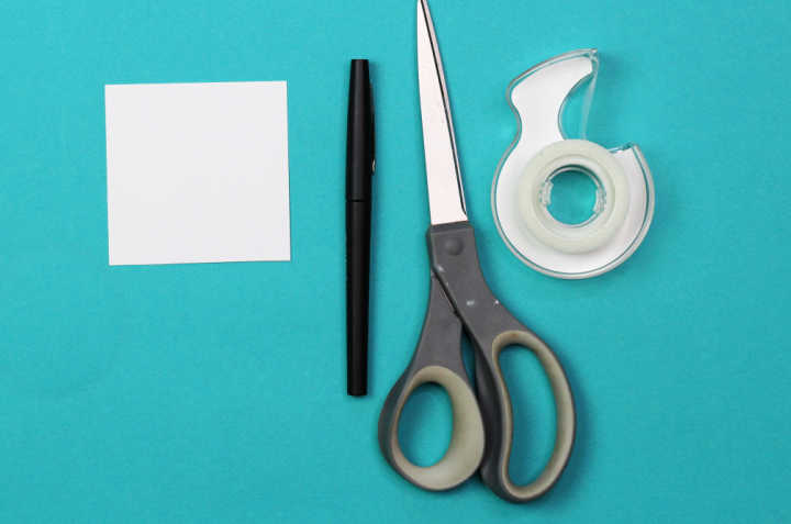Square paper, pen, scissors and roll of tape