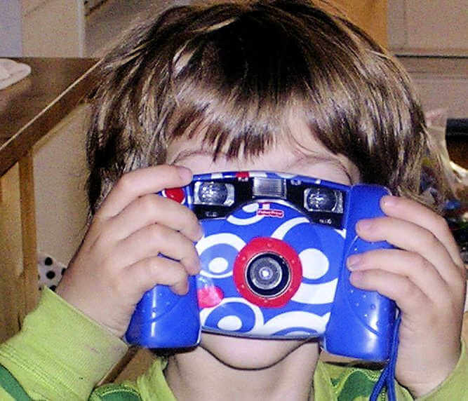 Child holding blue kid camera in front of his face