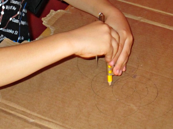Child drawing with compass to create mandala art