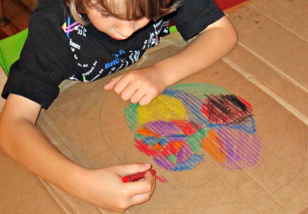 Child coloring in compass art with crayons