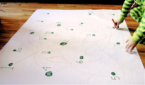 Child on floor completing giant dot to dot activity