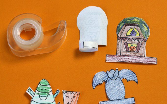 How to tape Halloween finger puppet tabs image shows tape dispenser and several puppets in stages of completion