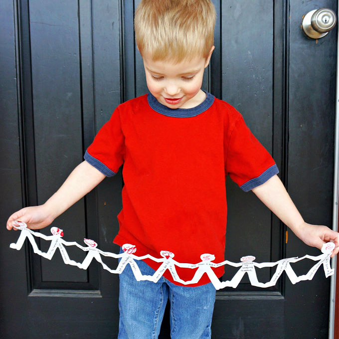 Boy holding giant paper doll chain hug