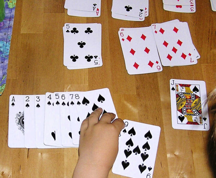 Child sorting playing cards by suit