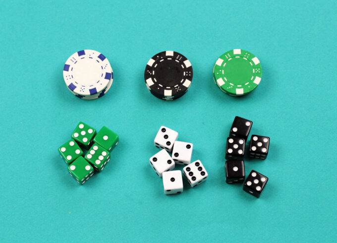 piles of white black and green casino chips and groups of five green, white and black dice