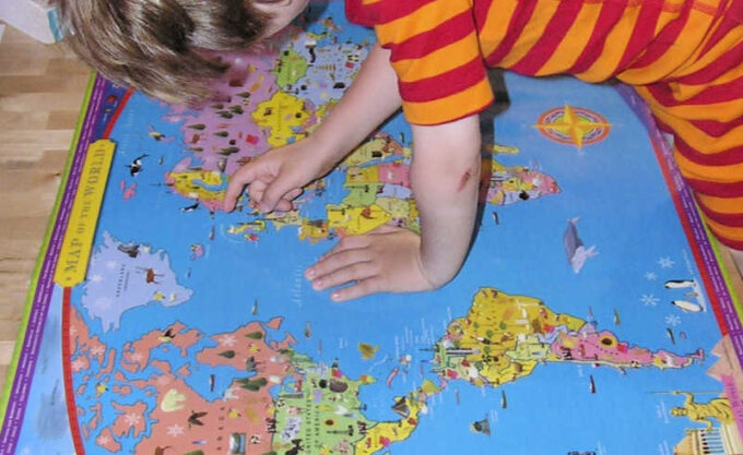 child looking at world map to learn geography