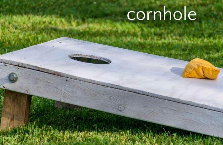 Cornhole board and yellow beanbag on lawn