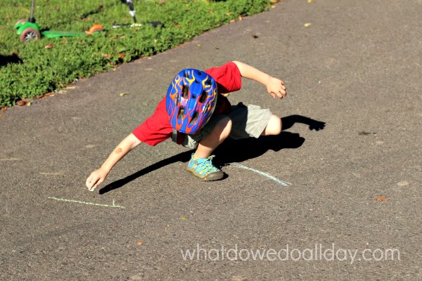 Drawing a scooter slalom outside with sidewalk chalk