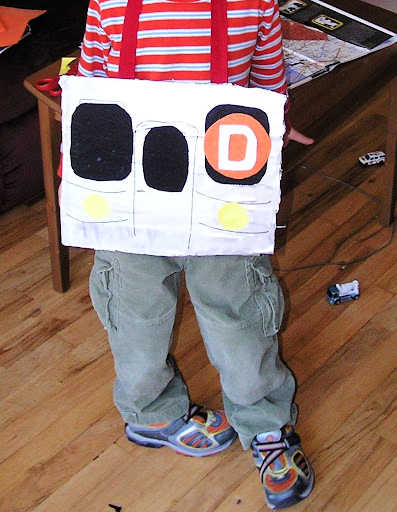 Child wearing a placard resembling front of a NYC subway train